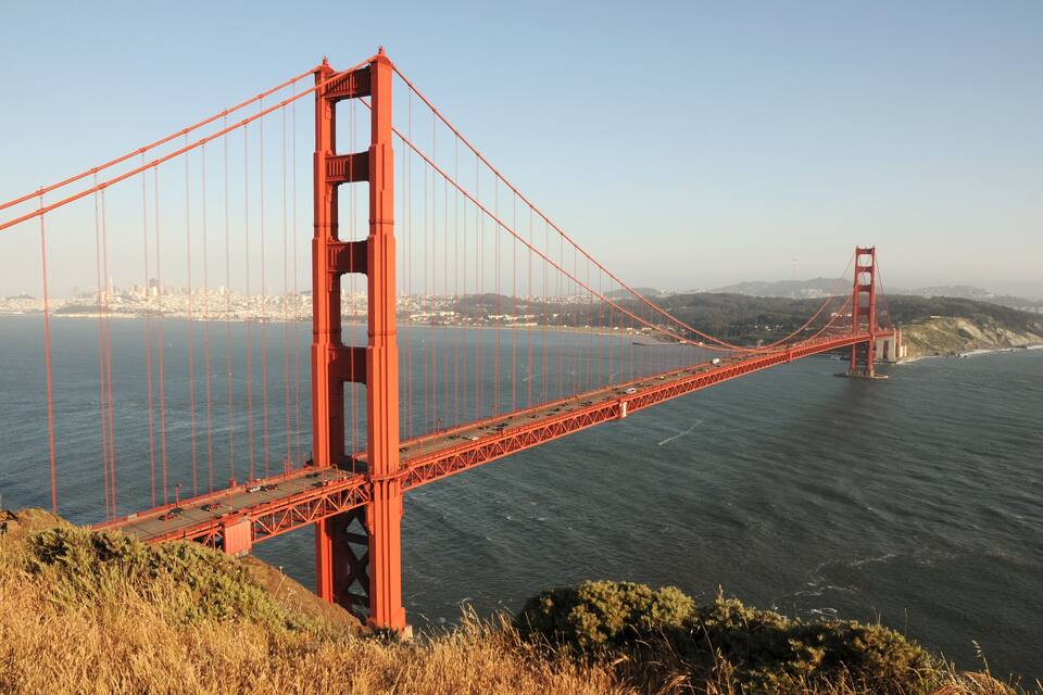 The Golden Gate Bridge spanning the Golden Gate Strait, with a city skyline in the background.