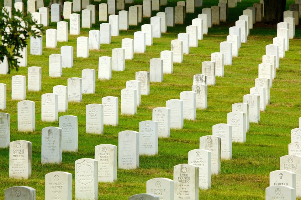 A cemetery with numerous headstones arranged in rows.