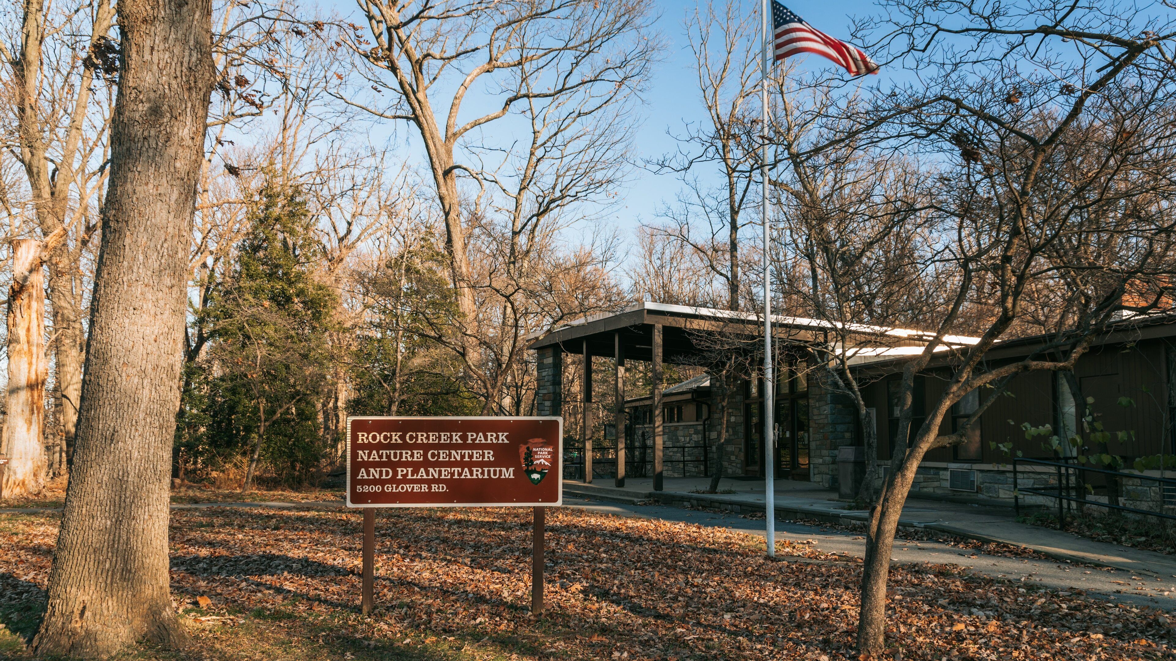 Schild für das Rock Creek Park Naturzentrum und Planetarium, im Hintergrund weht eine amerikanische Flagge.