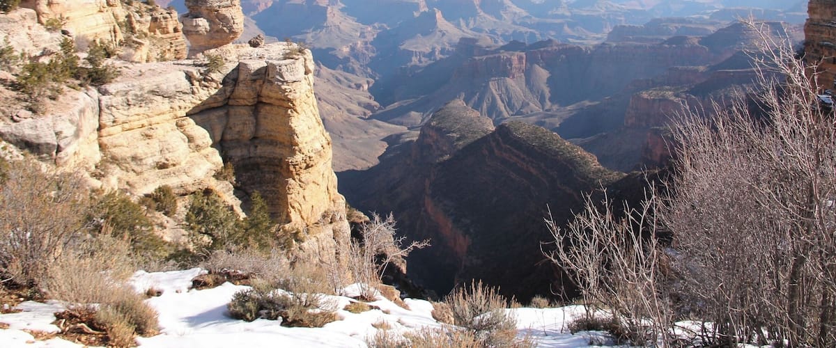 A canyon with layered rock formations and sparse vegetation.