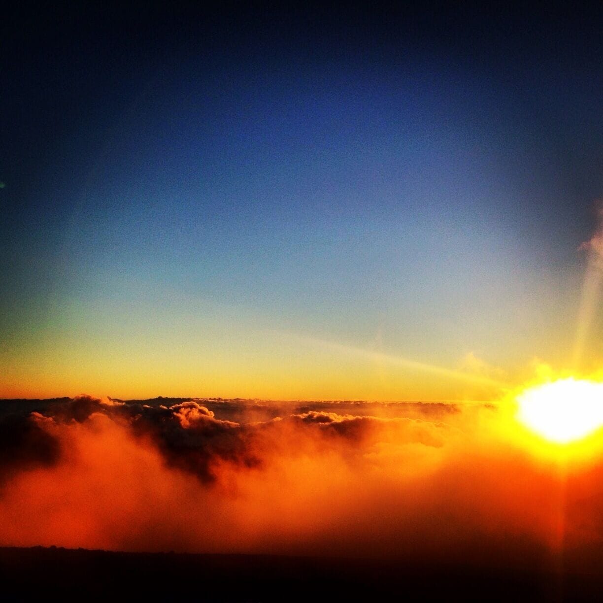 Un lever de soleil sur un paysage montagneux, avec des nuages.
