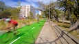 A cyclist on a green bike lane, a sidewalk, and buildings in the background.