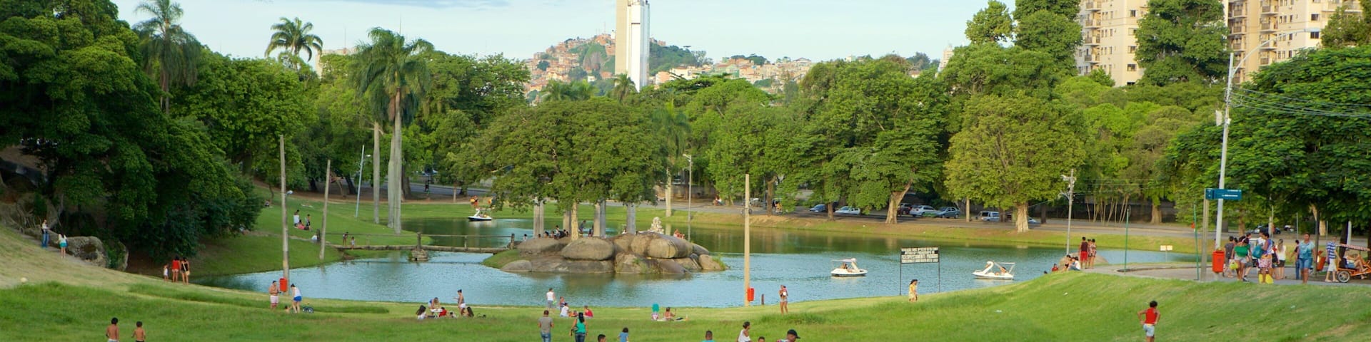 A park with a lake, boats, and people.