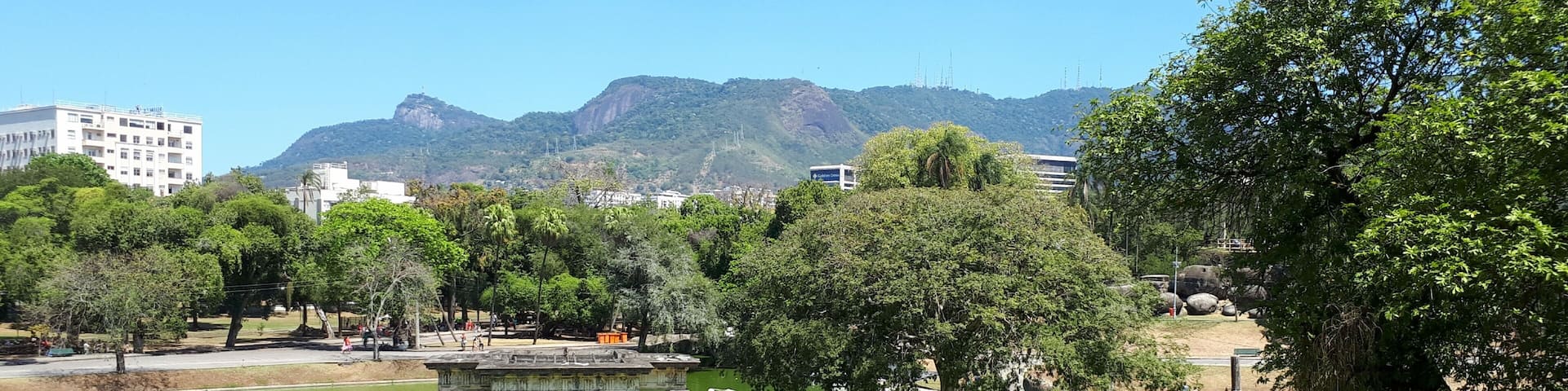 A park with a pond, a gazebo, and mountains in the background.