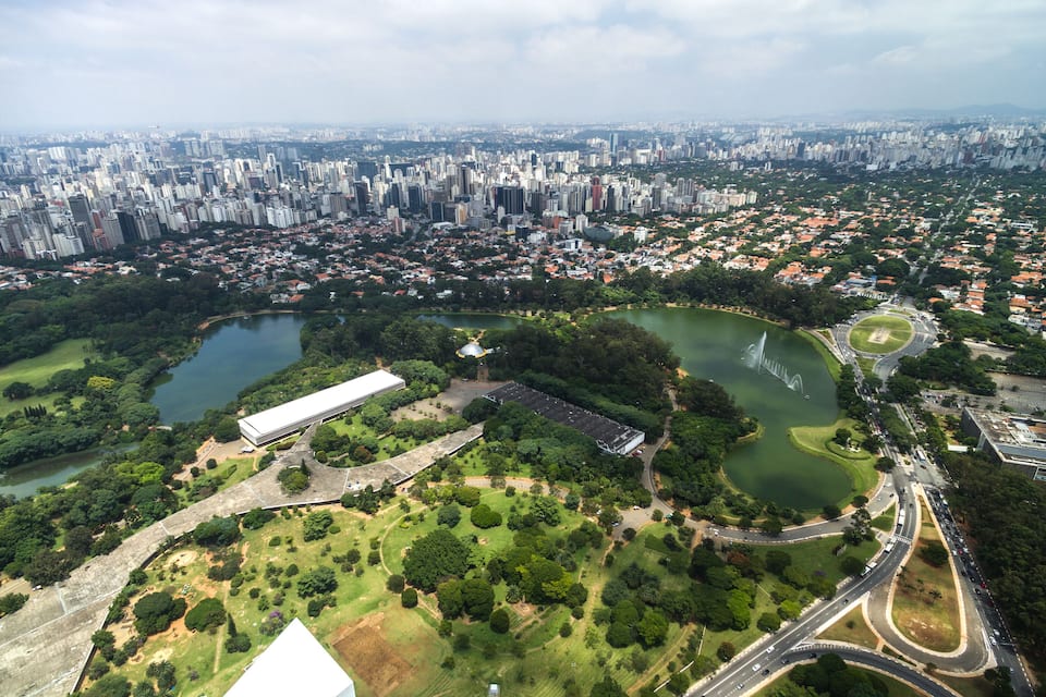 A cityscape with a large park, a lake, and a bridge.