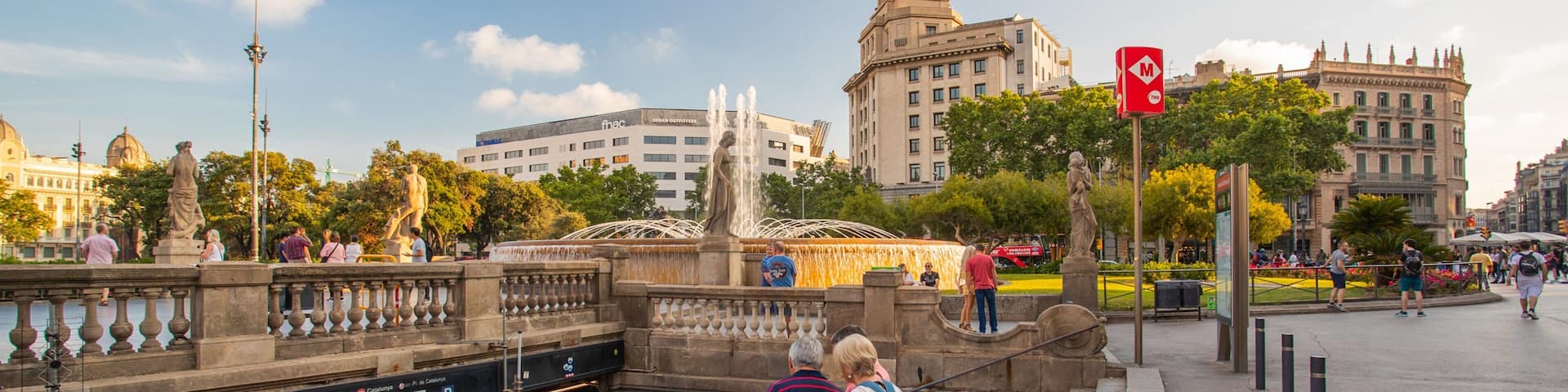 A public square with a fountain, statues, and historic buildings.