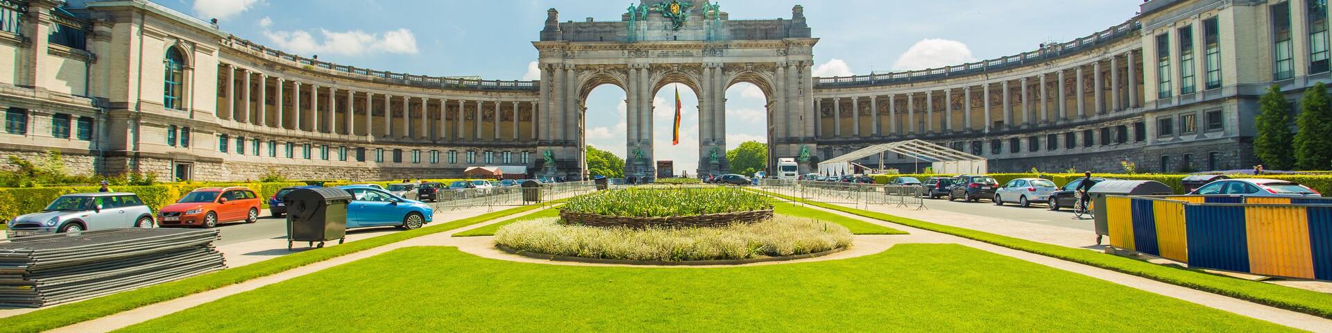 A large, historic building with a central archway and a well-maintained lawn in front.