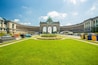 A large, historic building with a central archway and a well-maintained lawn in front.