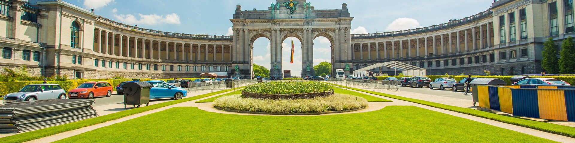 Un edificio grande e histórico con un arco central y un césped bien cuidado al frente.