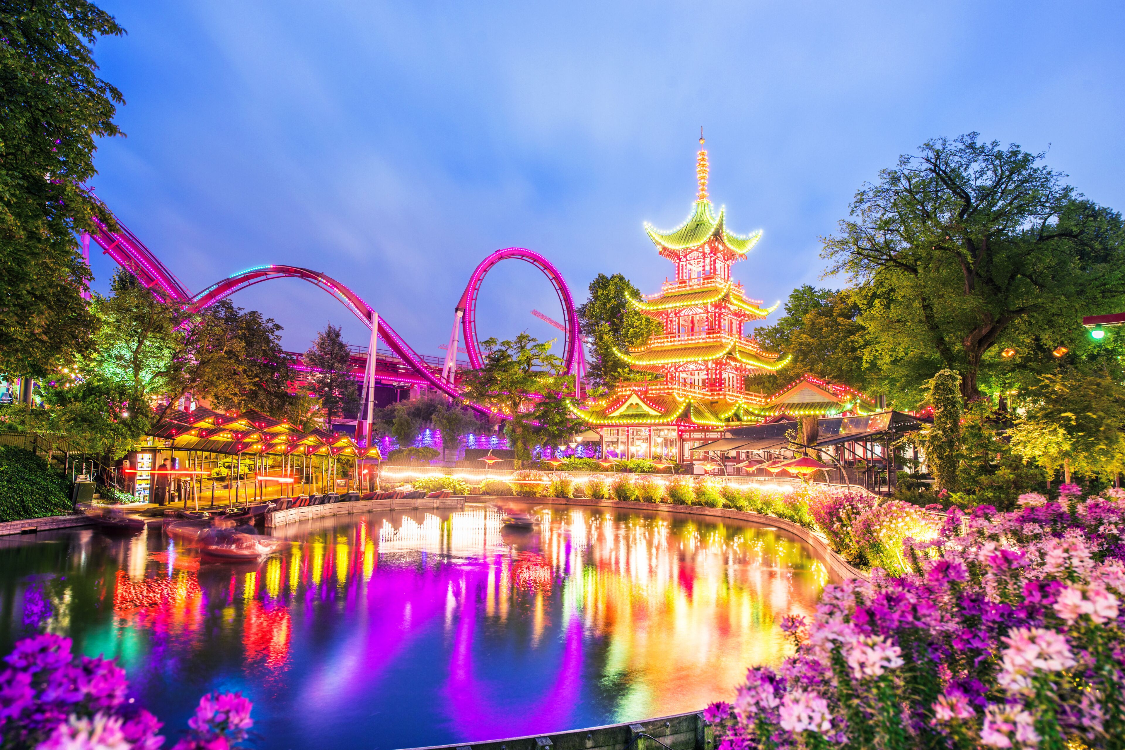breathtaking magical landscape in Tivoli Gardens in the evening with rides in the illuminations. Copenhagen, Denmark. Exotic amazing places. Popular tourist atraction.