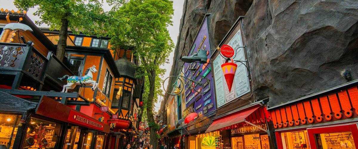 A narrow street lined with colorful shops and a large ice cream cone sign.