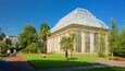 A large glass-domed building surrounded by green lawns and trees.