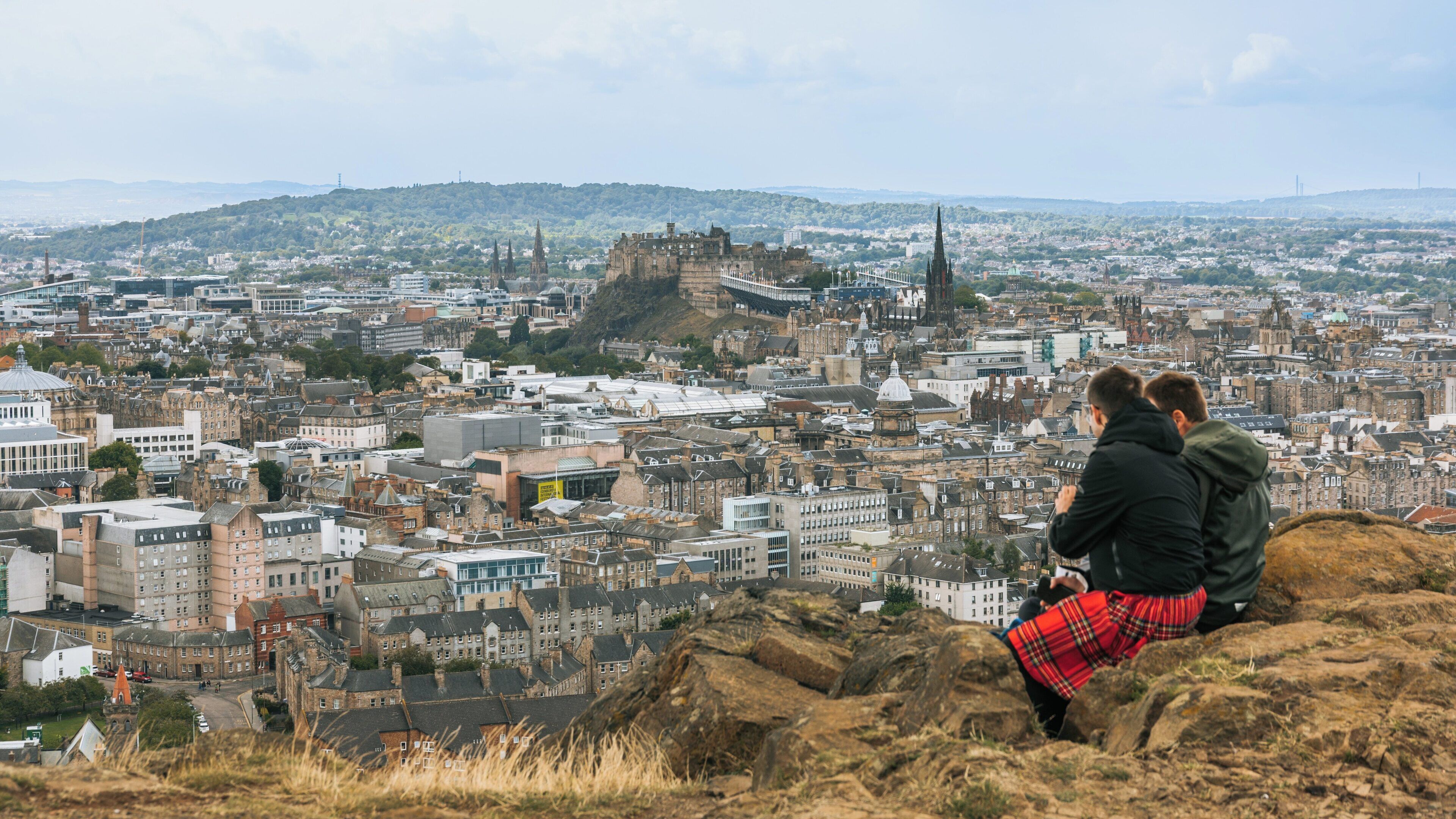 Stunning views of Edinburgh from Holyrood Park, showcasing city skyline, historic landmarks, and visitors enjoying the breathtaking scenery