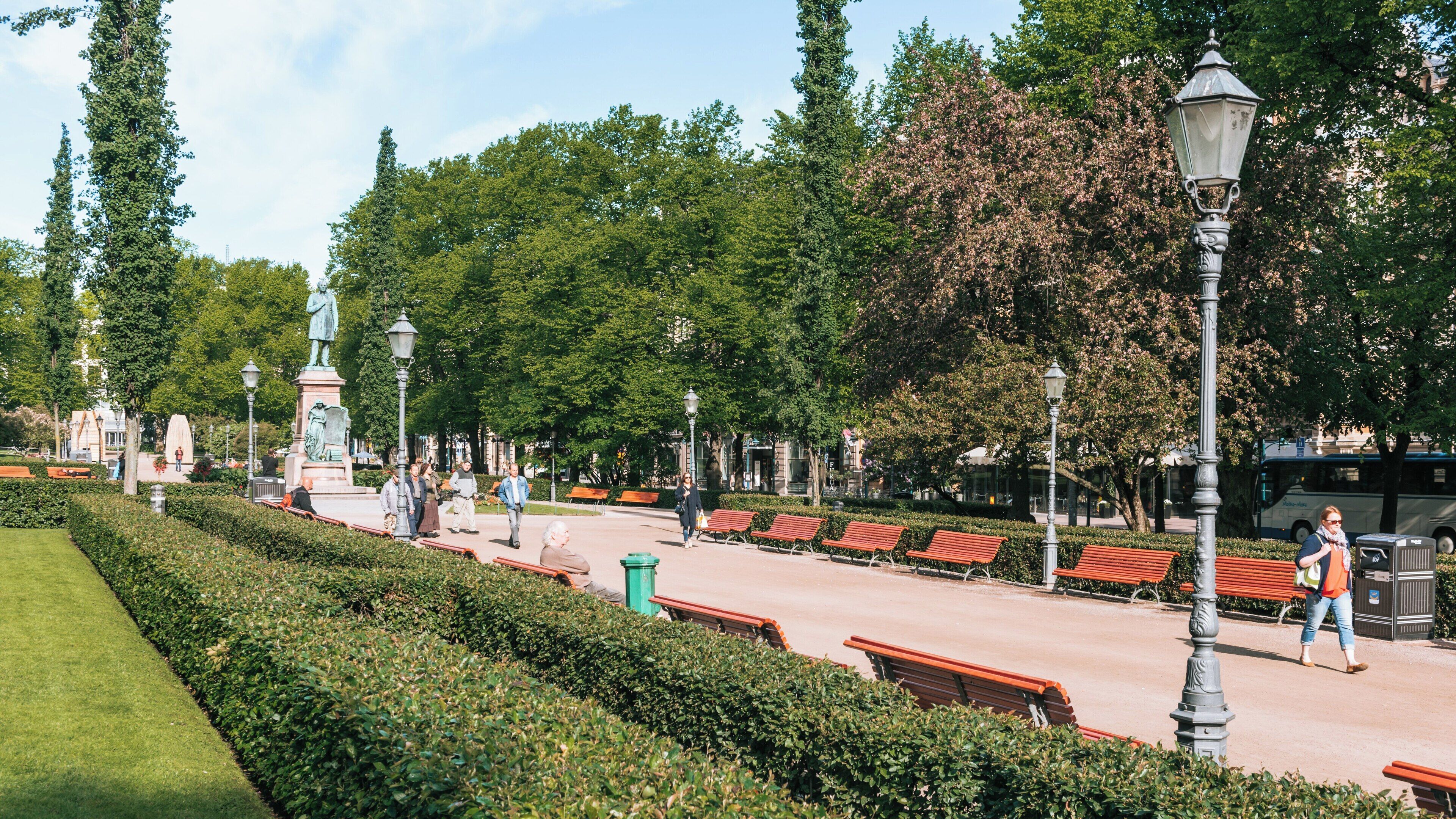 Strolling through Esplanadi Park in Helsinki, discovering green spaces and elegant benches on a sunny day