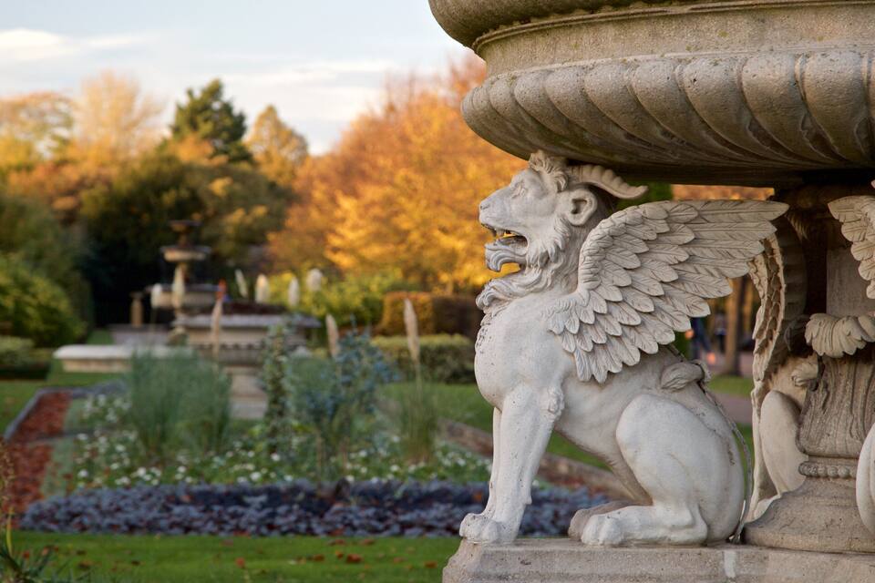 A stone lion statue with wings in a garden.