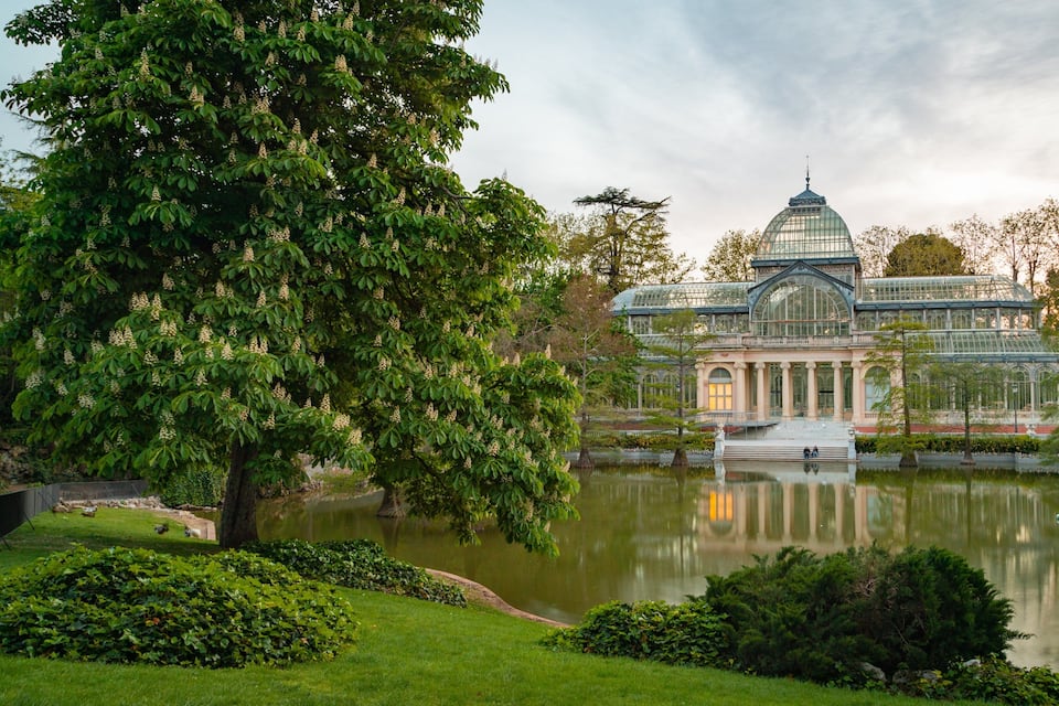 A large glass conservatory with a pond in front.