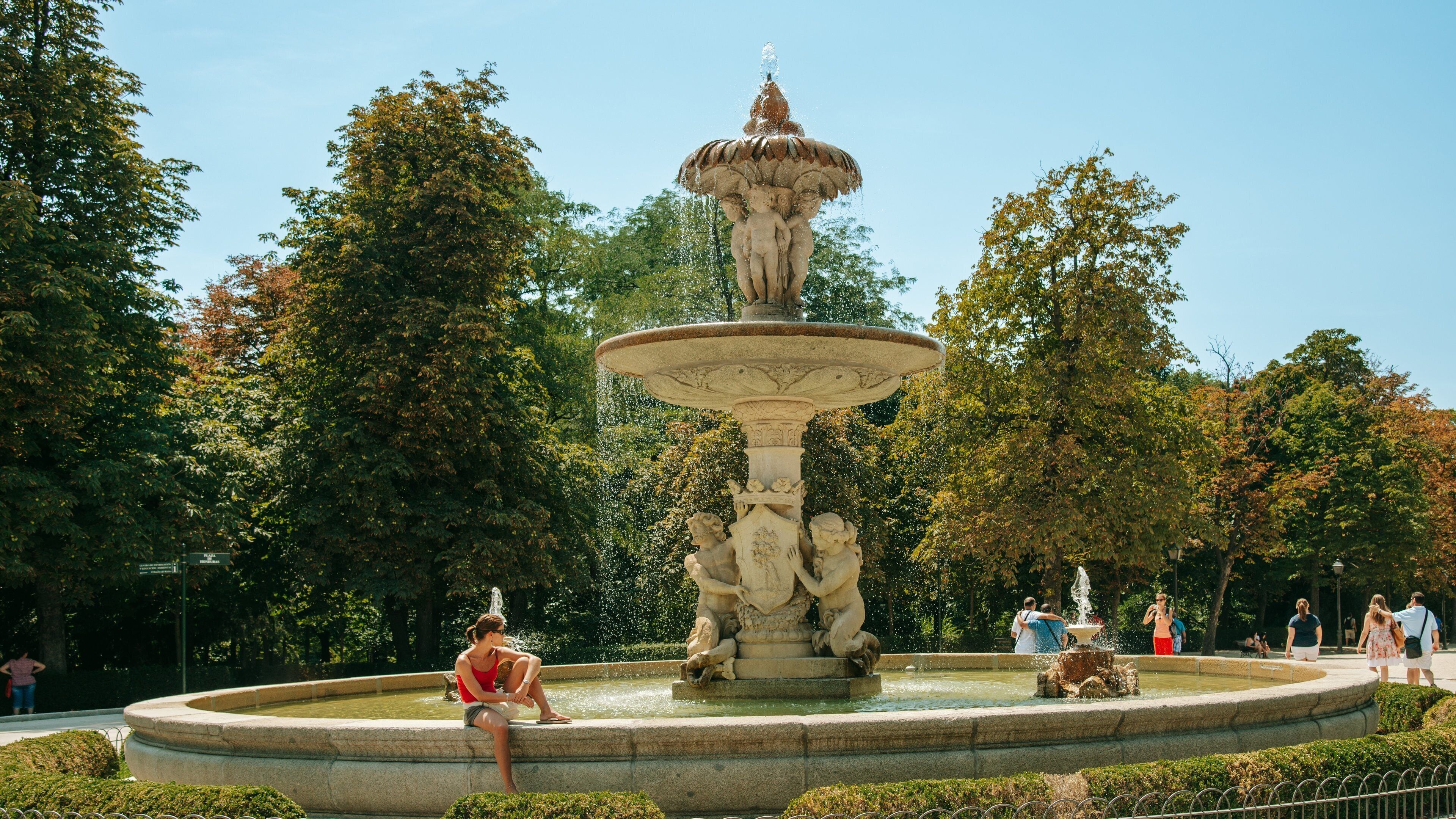 El Retiro Park showing a fountain and a garden as well as an individual femail