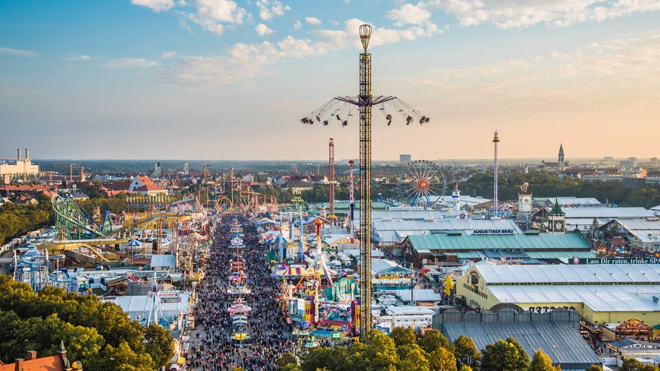 Ein lebhafter Vergnügungspark mit Riesenrad, Aussichtsturm und verschiedenen Fahrgeschäften.