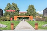 Un vialetto conduce all'ingresso di un museo, con indicazioni direzionali, immerso nel verde e alberi.
