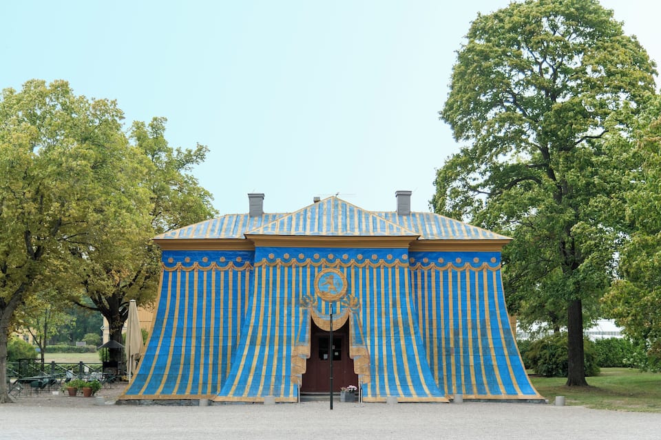 Un edifici amb parets de franges blava i groga i un arc central.