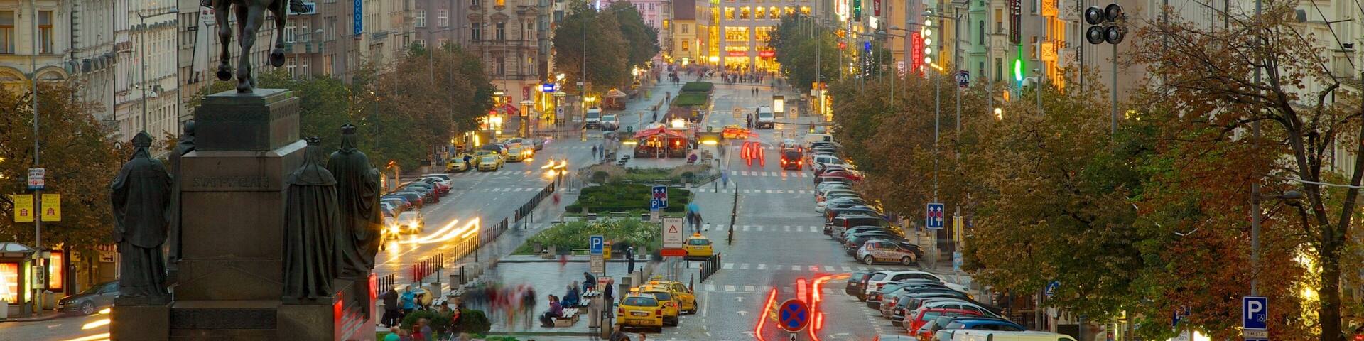 A busy urban street lined with historic buildings and a statue.