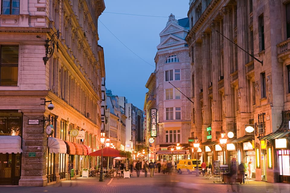 Una vivace strada al crepuscolo, con edifici decorati e lampioni.