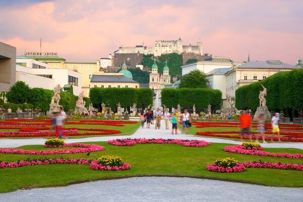 Ein Garten mit Statuen und einer Burg im Hintergrund.