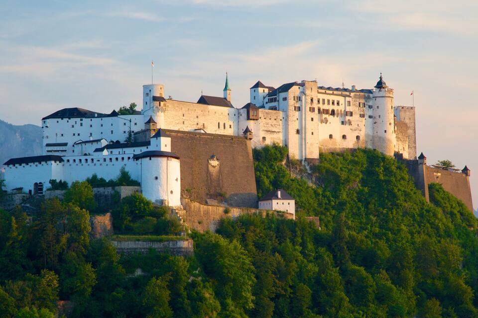 A historic castle on a hill with lush greenery.