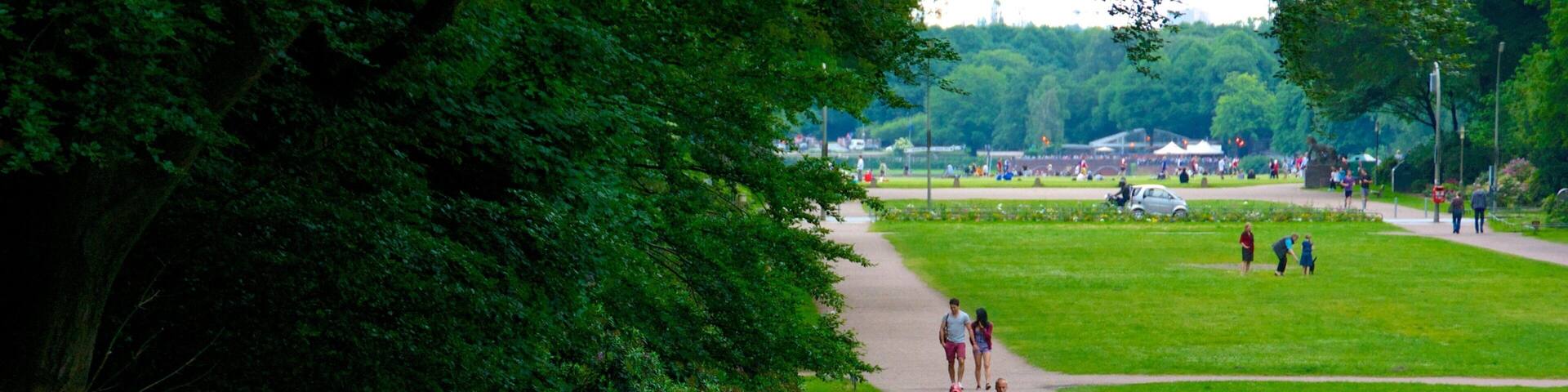 A park with a paved path, greenery, a bicycle, and people walking.