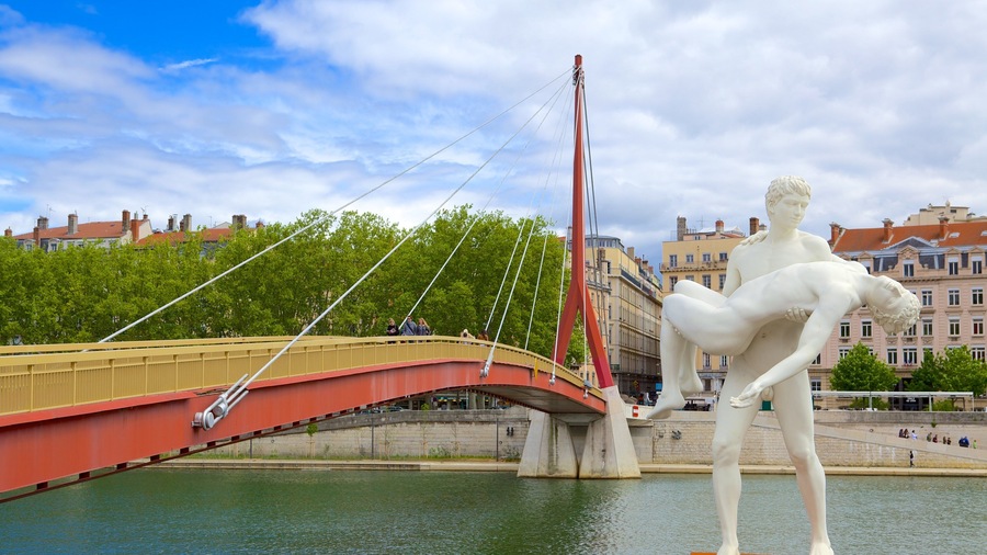A red bridge over a river with a white statue of a man in a dynamic pose.