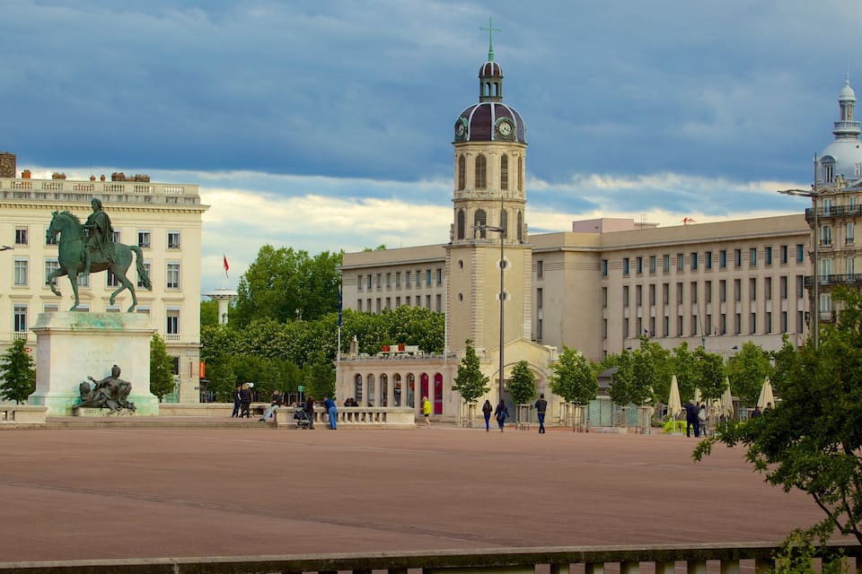 A historic plaza with a statue of a man on a horse, a clock tower, and the Hotel Royal building.