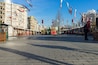 A tram in a city square with buildings and flags.