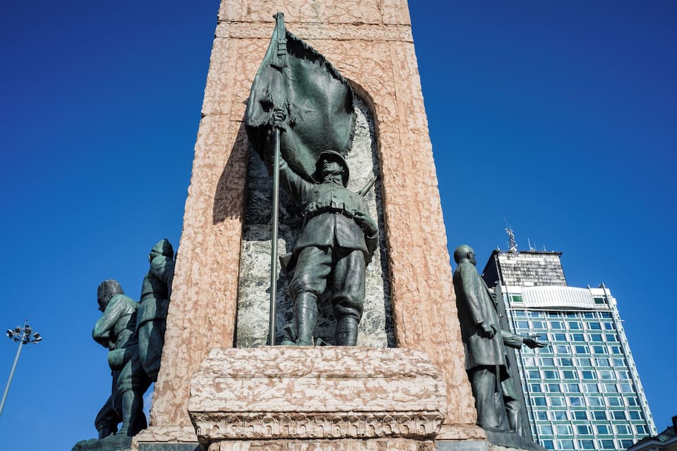 A statue of a soldier holding a flag, with a building in the background.