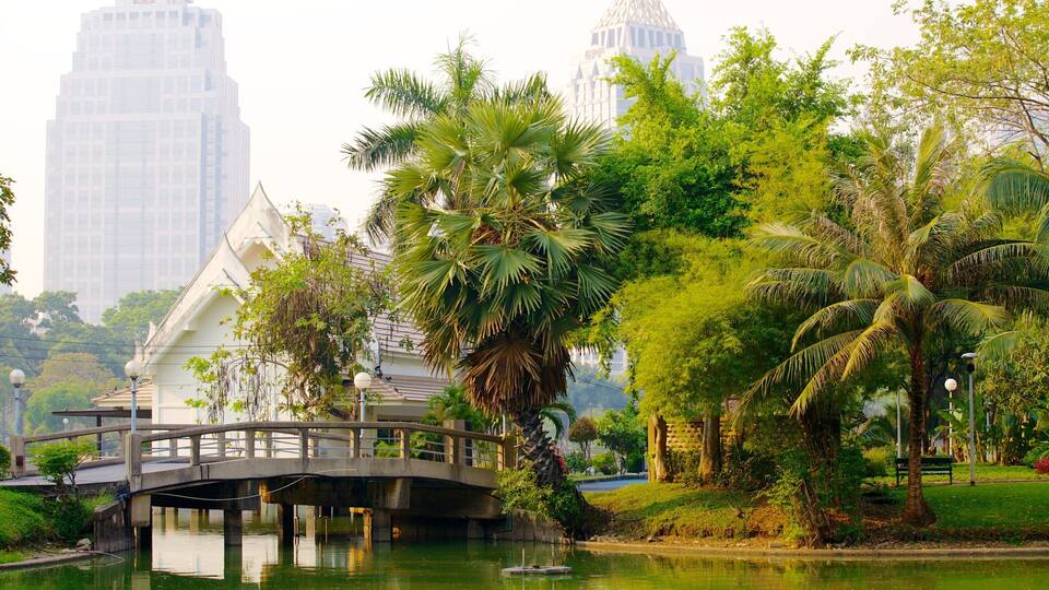 Uma ponte sobre a água, palmeiras e edifícios modernos ao fundo.