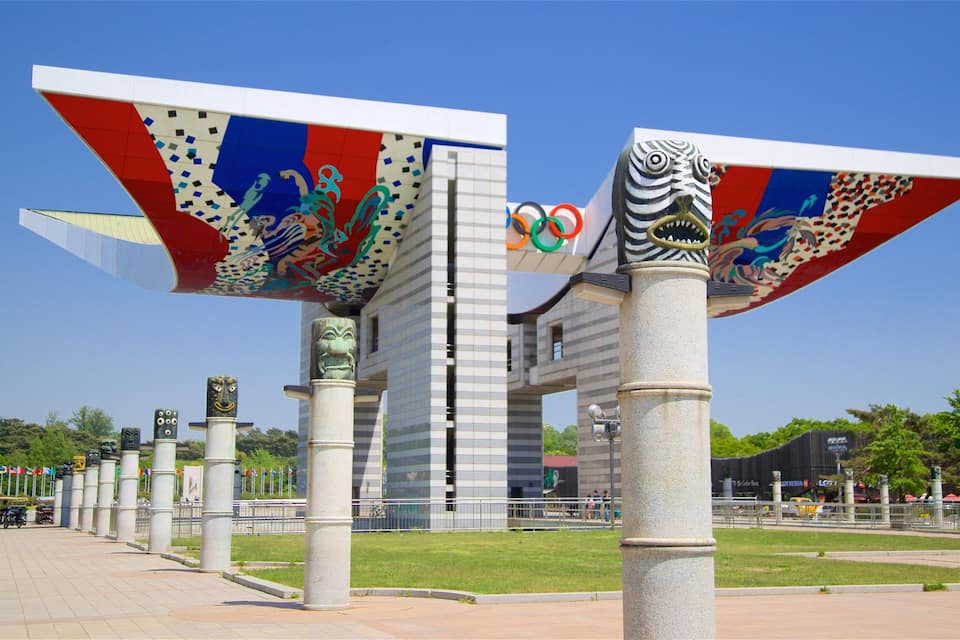 Ein modernes Gebäude mit einzigartigem Dachdesign und farbenfrohen Mustern sowie den Olympischen Ringen.