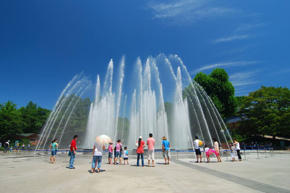 A large fountain with water jets shooting up against a clear blue sky.