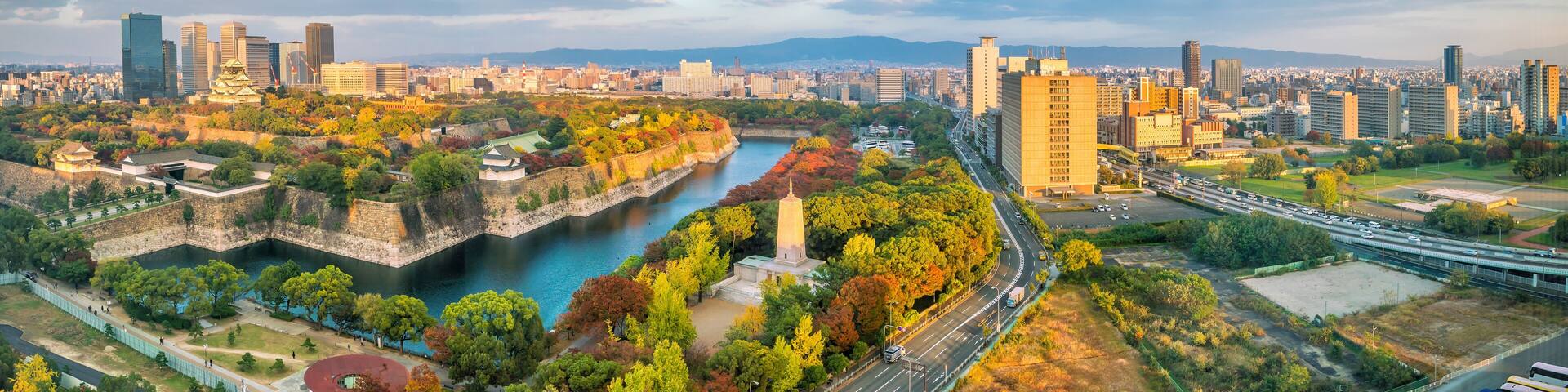 A cityscape with a river, a traditional temple, and modern high-rises.