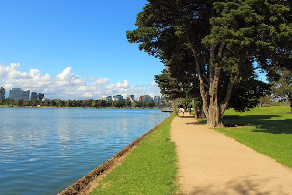 Un parc avec un lac, un sentier pédestre et, en arrière-plan, la silhouette de la ville.