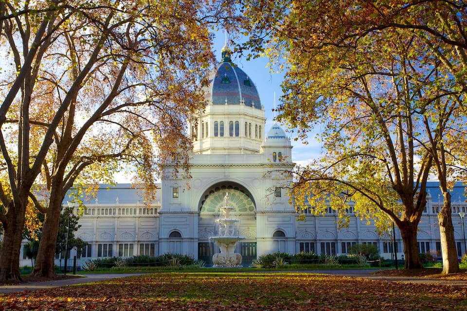 A large white building with a dome and arched windows, surrounded by trees with autumn leaves.