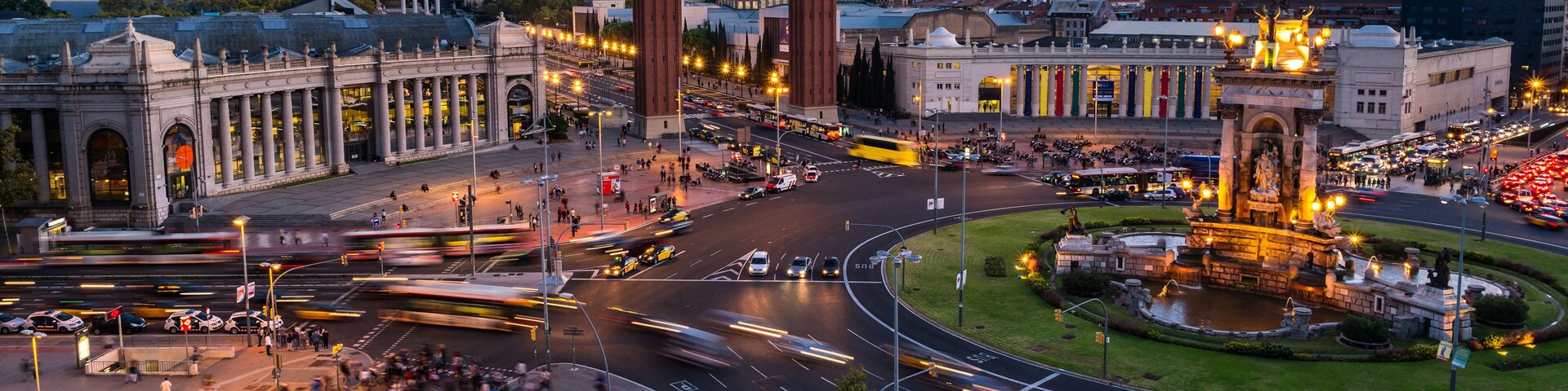 Una concurrida intersección urbana con edificios históricos, una glorieta y una fuente central.