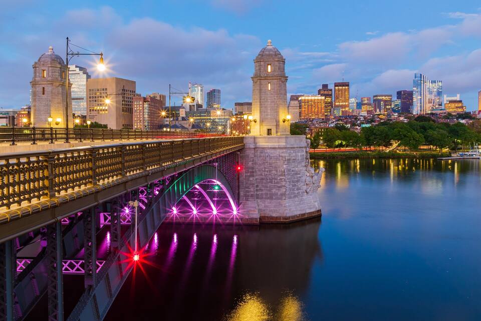 A bridge with illuminated lights and a cityscape in the background.