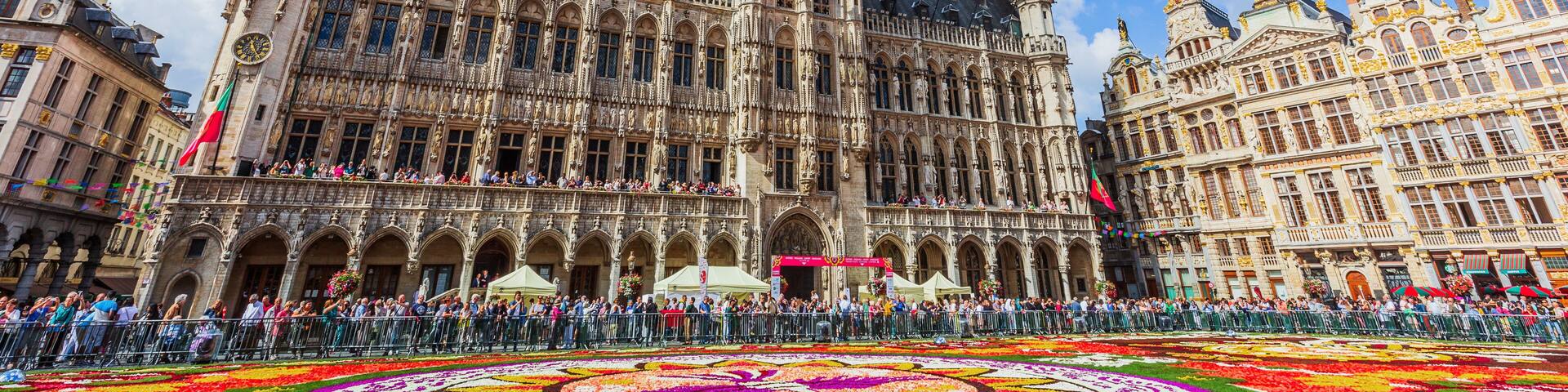 A historic building with intricate architecture, a prominent tower, and a colorful flower arrangement in the foreground.