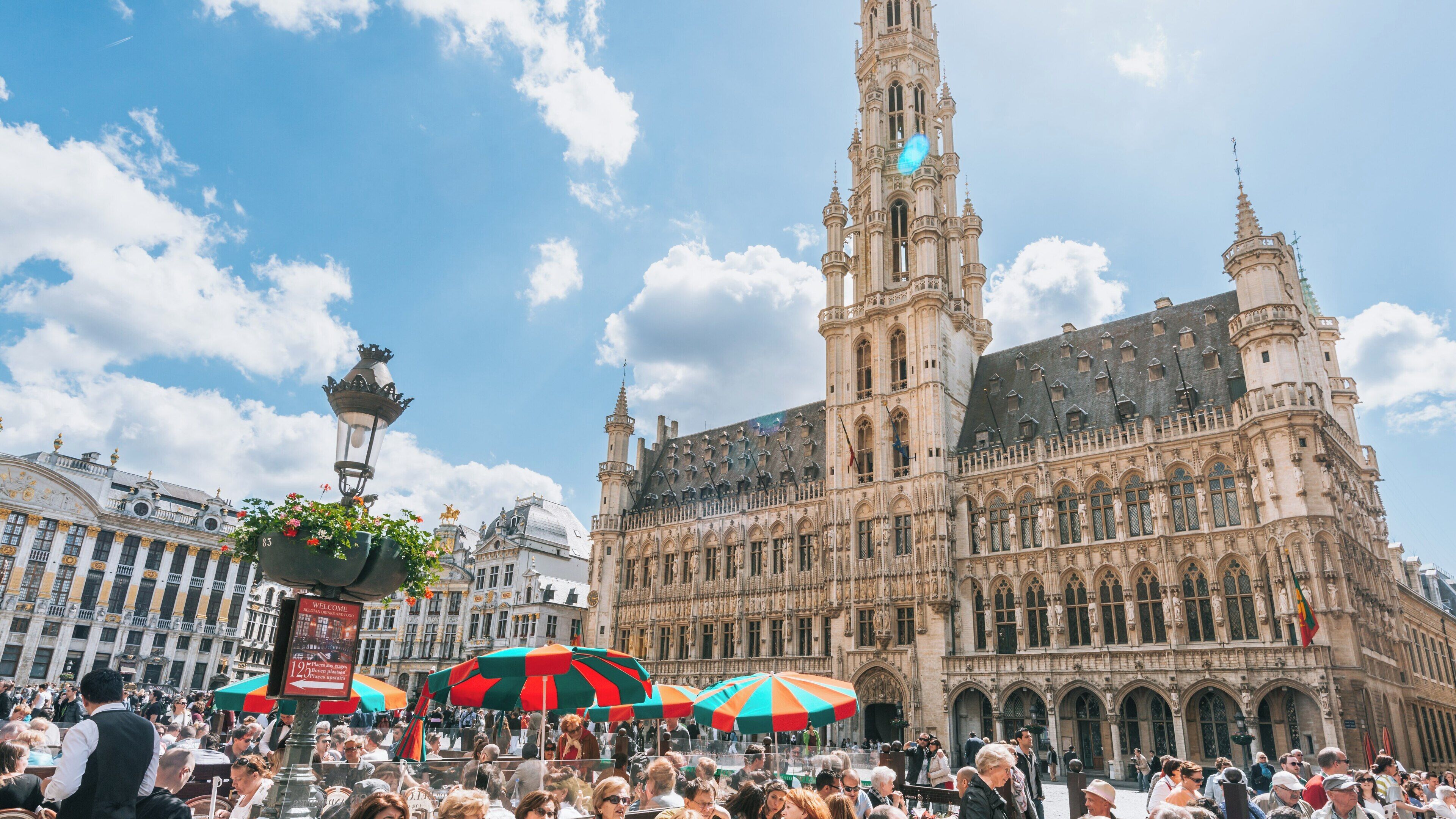 Explore the vibrant atmosphere of La Grand Place in Brussels, where historic architecture meets lively crowds under a bright sky