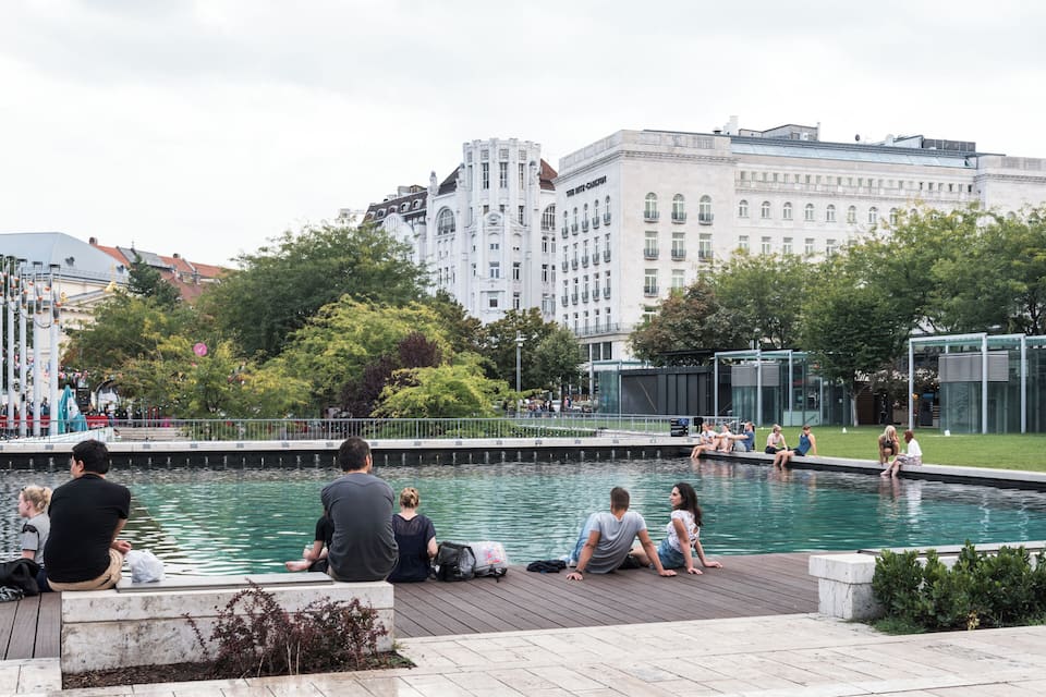 A public swimming pool surrounded by trees and buildings.