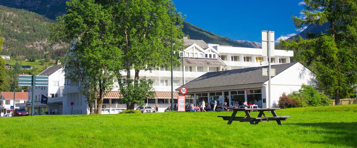 A picnic area with a mountain backdrop, a white building with a red sign, and a clear blue sky.