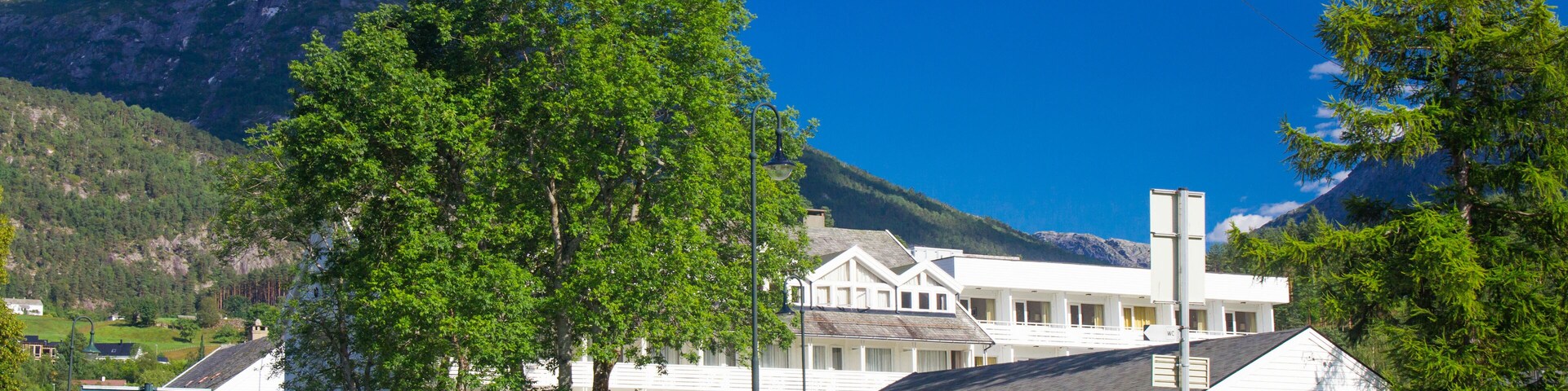 A picnic area with a mountain backdrop, a white building with a red sign, and a clear blue sky.