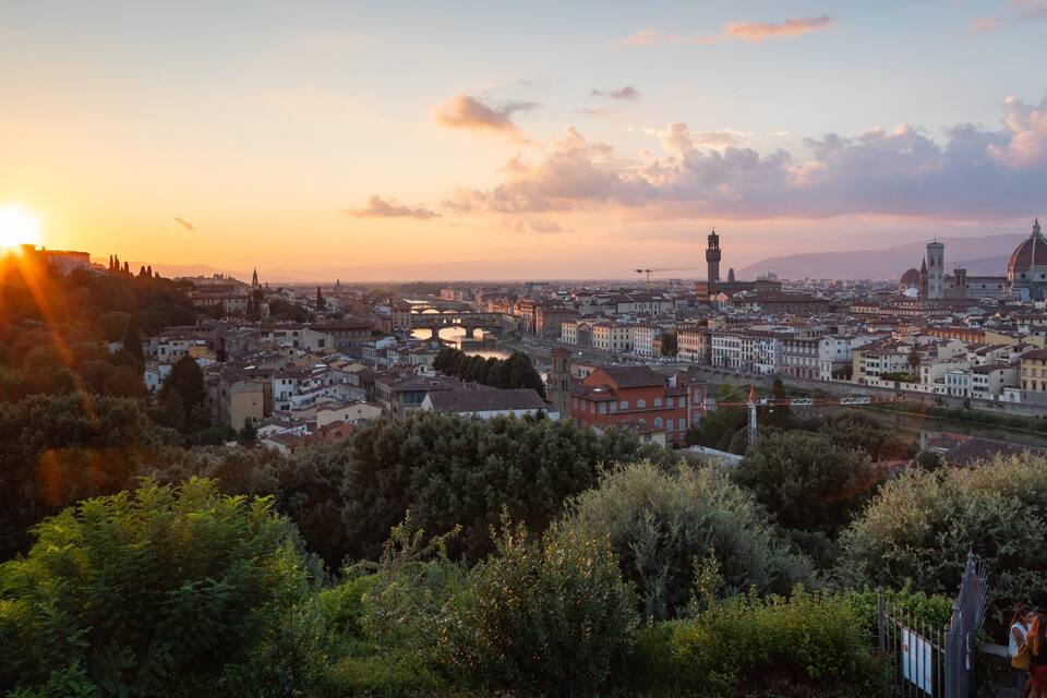 Un paisaje urbano al atardecer con arquitectura histórica destacada, incluyendo un campanario y una cúpula.