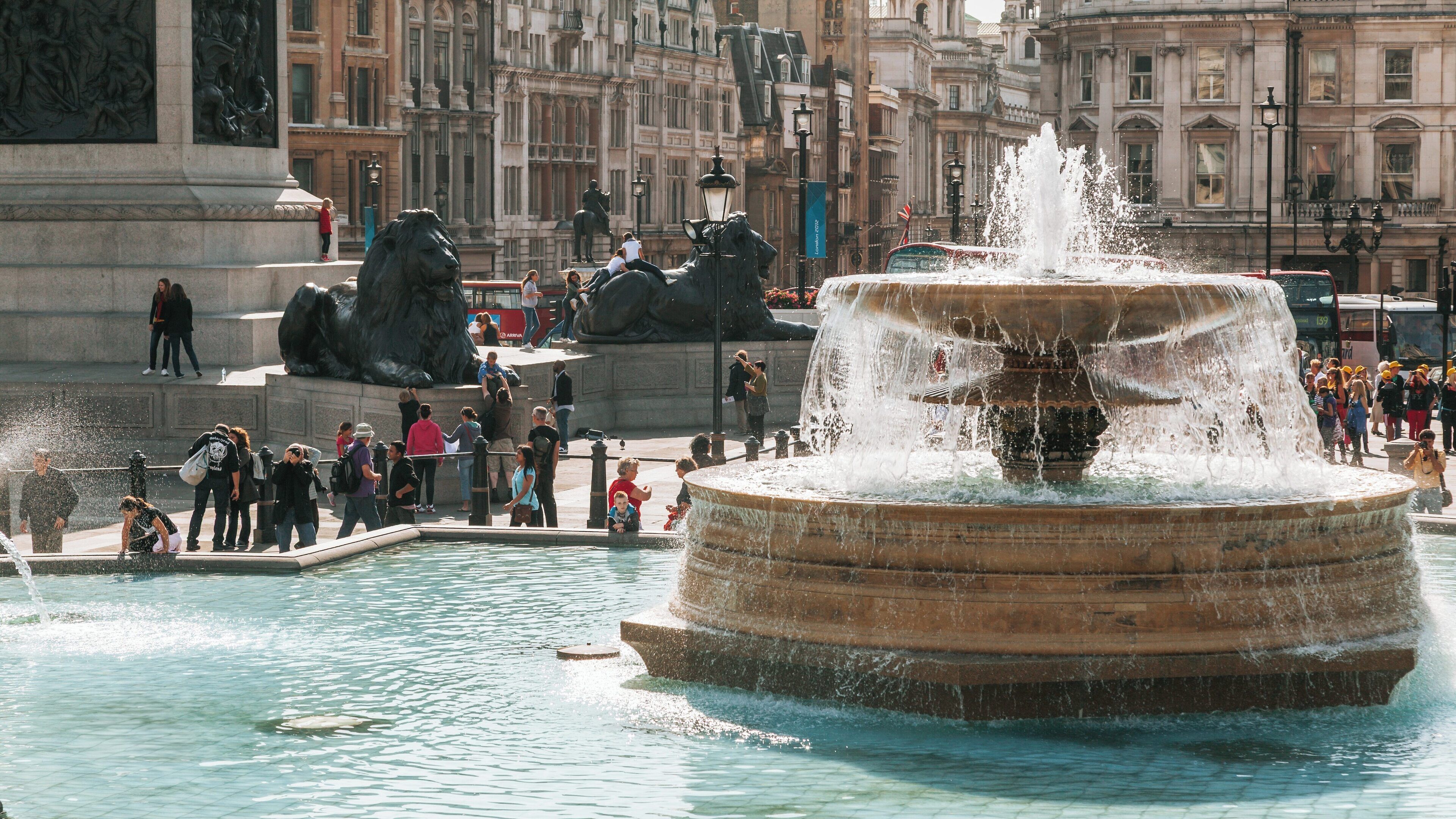 Visitors enjoy a sunny day at Trafalgar Square in Soho, London, with the iconic fountain and majestic lions on display