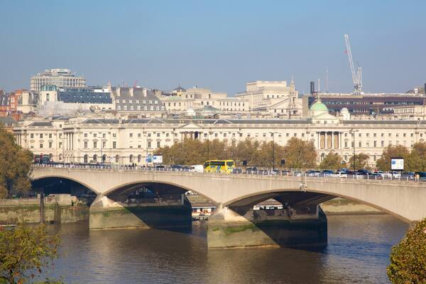 A bridge over a river with buildings in the background.