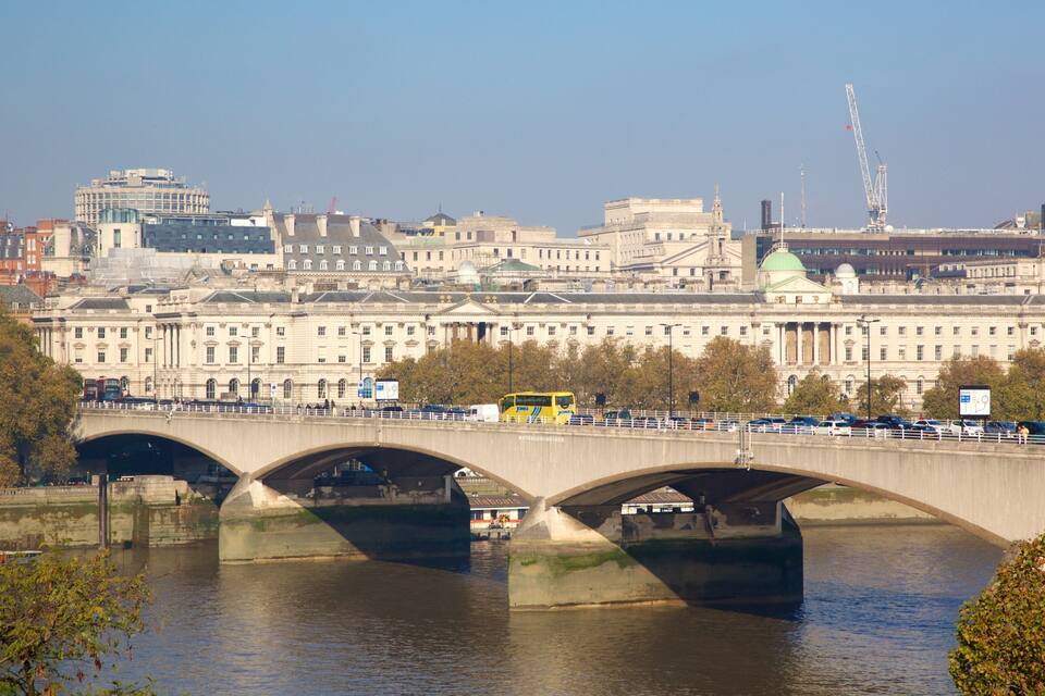 A bridge over a river with buildings in the background.